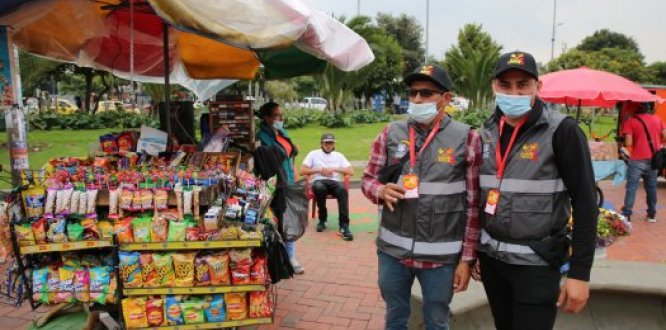 Dos vendedores informales, que firmaron acuerdo de espacio público en el Portal de Suba, con sus chalecos de economía popular y sus productos.