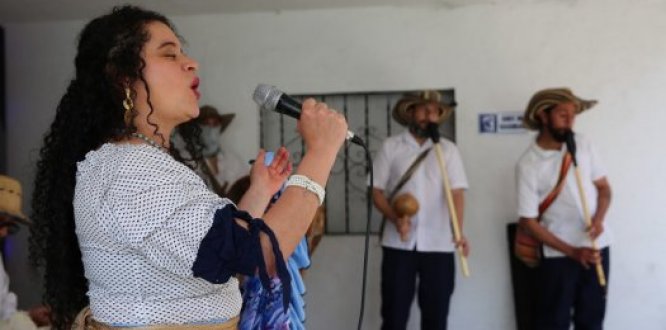 Una mujer cantando con un grupo musical de Cumbia al fondo.